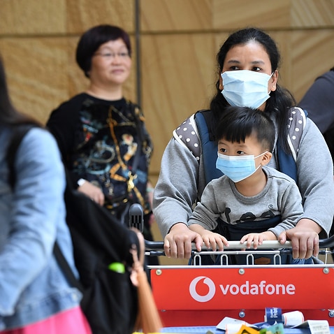 Passengers wearing protective masks arrive at Sydney International Airport