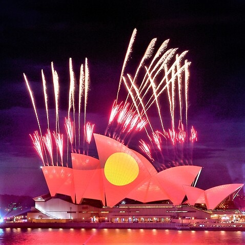 Fireworks are seen as the Aboriginal flag is projected onto the sails of the Sydney Opera House during Australia Day celebrations. 