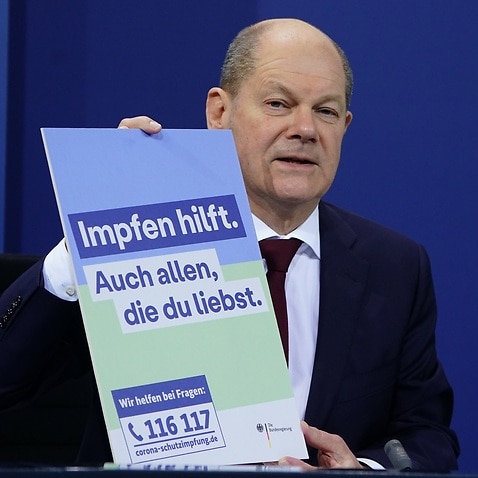 German Chancellor Olaf Scholz holds sign saying 'vaccination helps' 