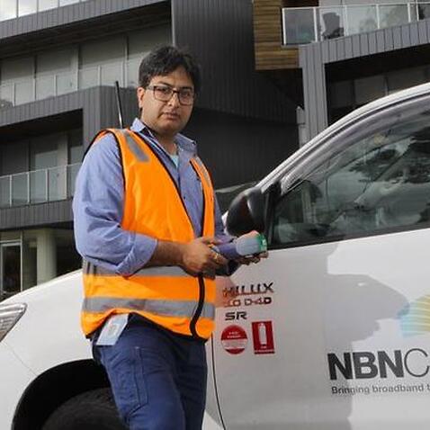 NBN technician Rajav Kapil in front of an apartment block that has been connected to the National Broadband Network (NBN) in Brunswick, Melbourne,  Tuesday, March 11, 2014. (AAP Image/David Crosling) NO ARCHIVING