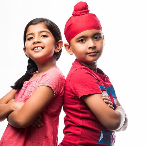 Cute little sikh/punjabi boy and girl standing isolated over white background, facing camera