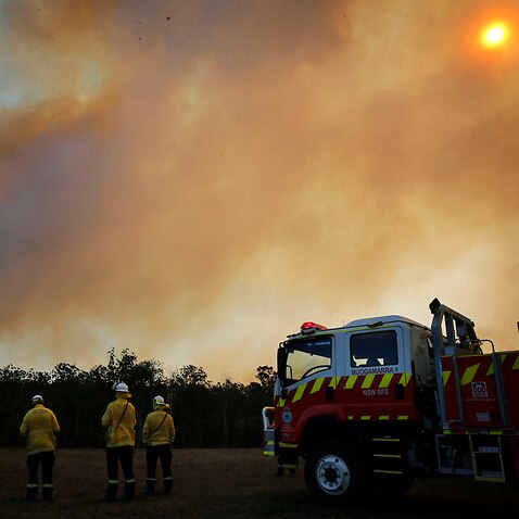 Firefighters observe the movements of a fire at a property at Old Bar, New South Wales.