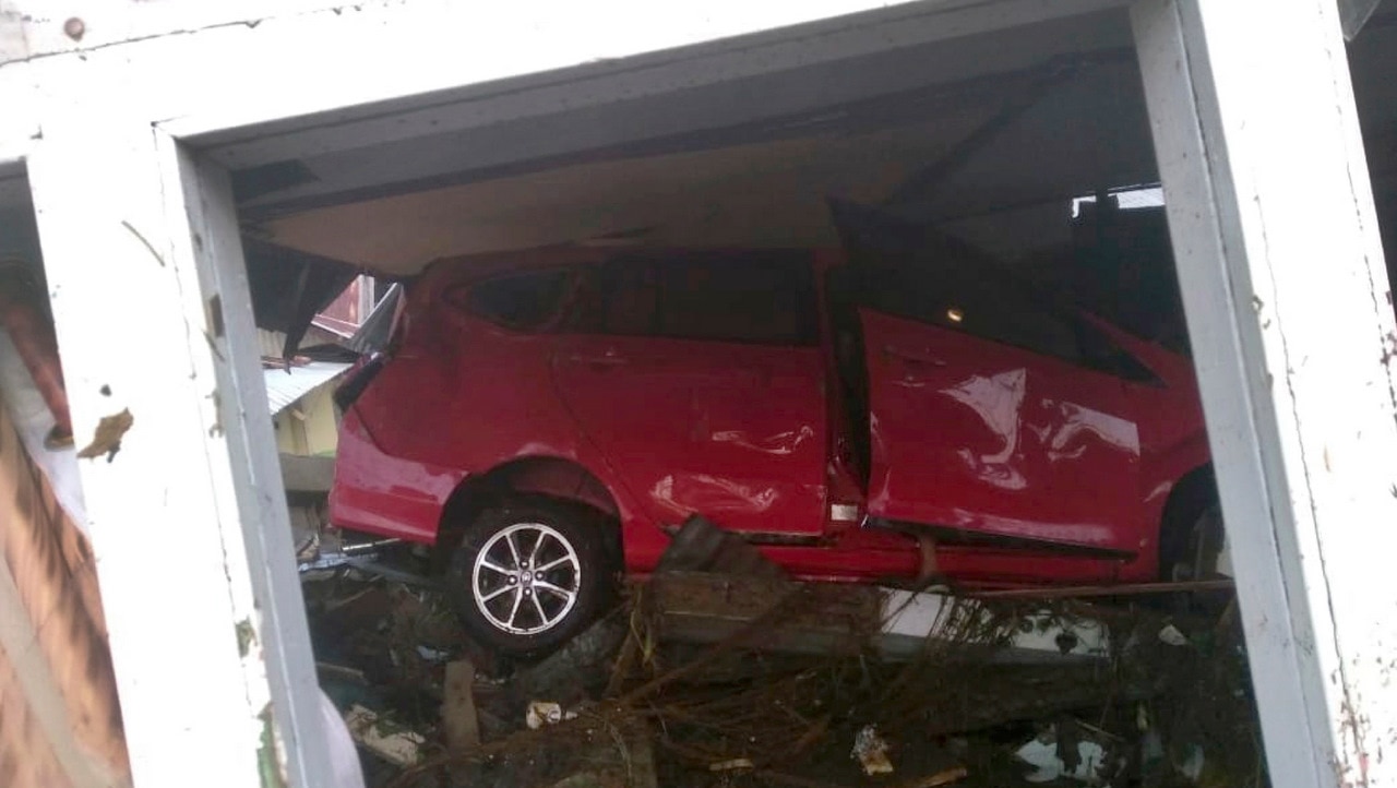 A tsunami-swept car is seen stuck under a damaged building in Palu, central Sulawesi, Indonesia.