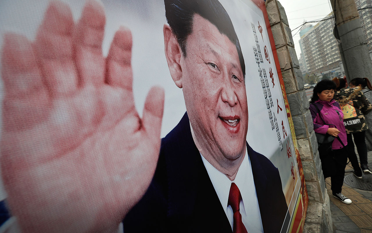 Women walk by a poster featuring Chinese President Xi Jinping and his China Dream in Beijing, Thursday, Oct. 26, 2017. 