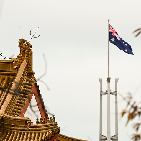 The flag pole of the Australian Parliament is seen behind the roofs of the Chinese Embassy in Canberra, Monday, June 29, 2020. (AAP Image/Lukas Coch) NO ARCHIVING