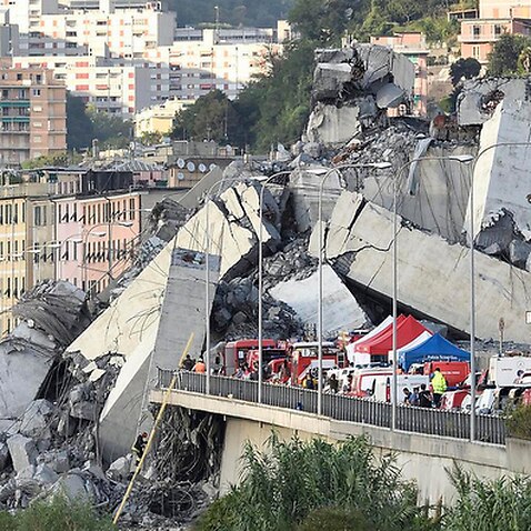 Rescuers work to recover an injured person after the Morandi highway bridge collapsed in Genoa, northern Italy, Tuesday, Aug. 14, 2018. 