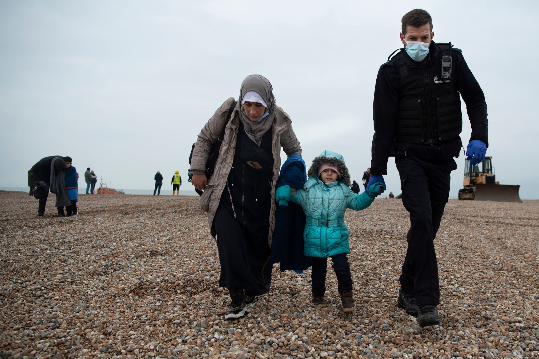 A member of the UK Border Force helps migrants on a beach in Dungeness on 24 November, 2021, after they were rescued while crossing the English Channel. 