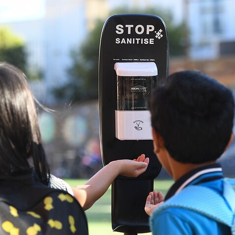 Students use a hand sanitiser station as they arrive to Carlton Gardens Primary school in Melbourne.