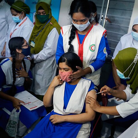 A health worker administers a dose of Pfizer-BioNTech COVID-19 Vaccine to a student at Ideal School and College in Dhaka, Bangladesh.