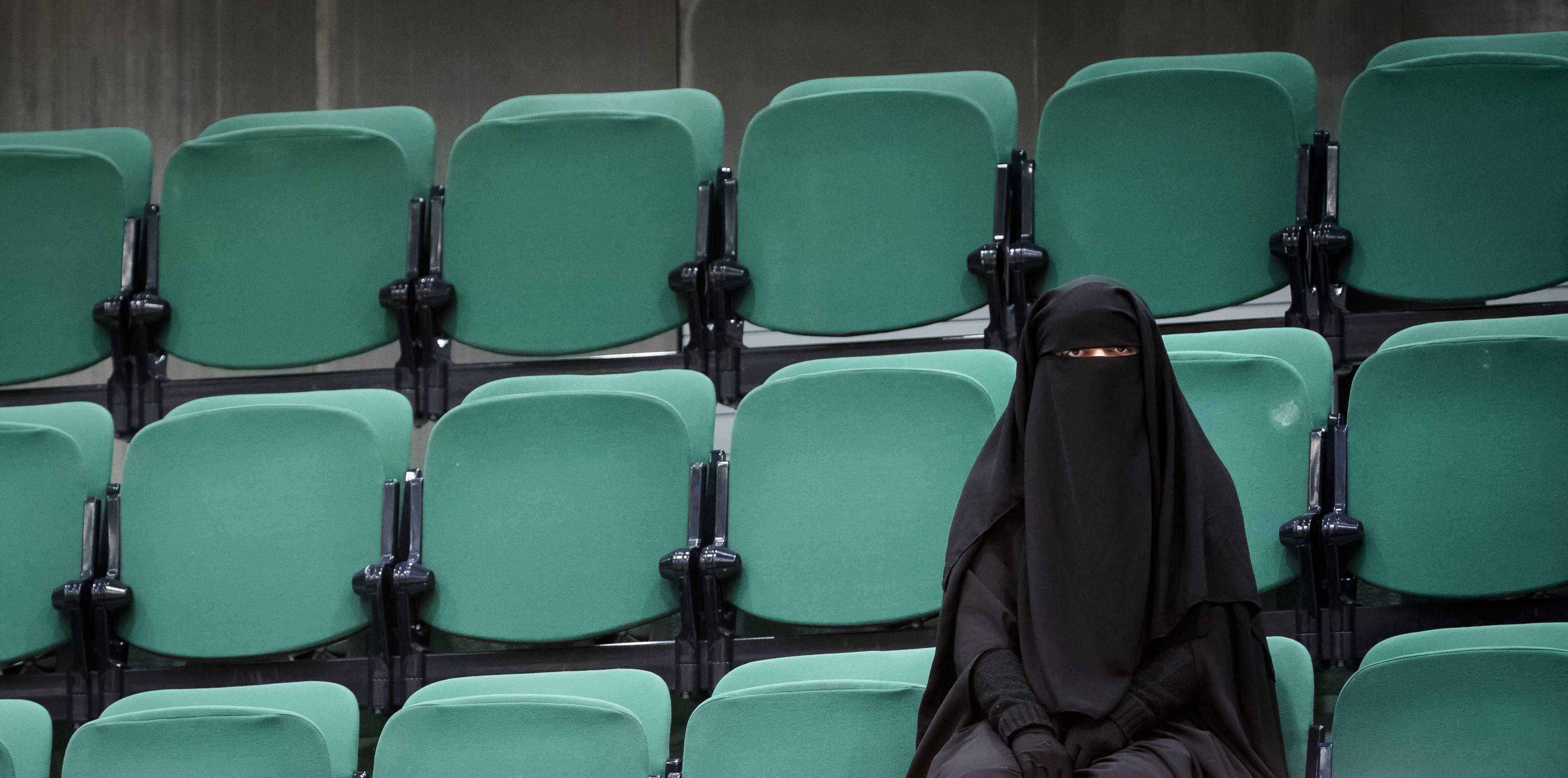 A Burqa-clad woman sits at the public gallery of visitor's section, before the debate on face covering clothing.