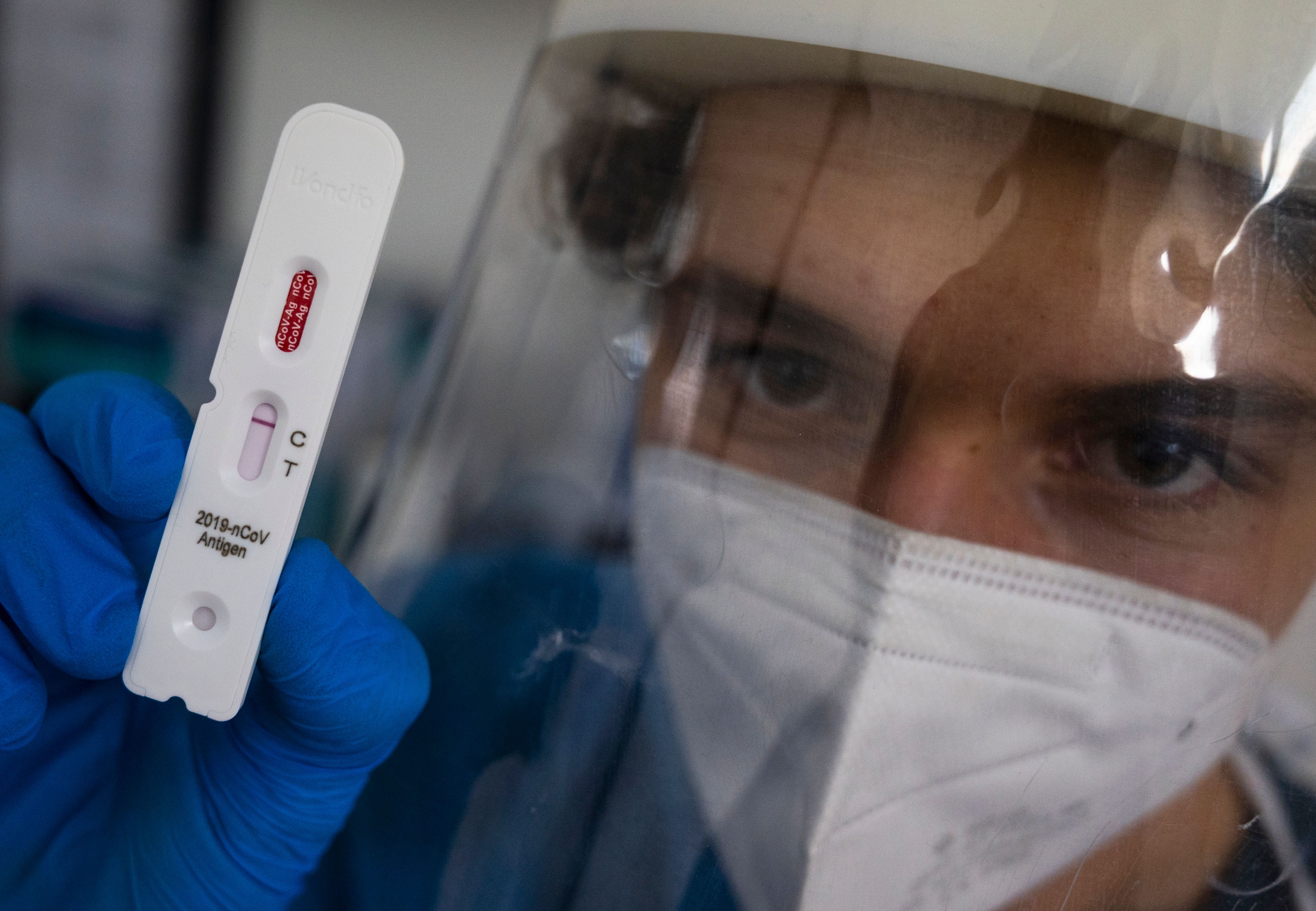 A health professional poses with a test cassette used for a COVID-19 rapid antigen test at a testing centre in Berlin on 17 February, 2021. 