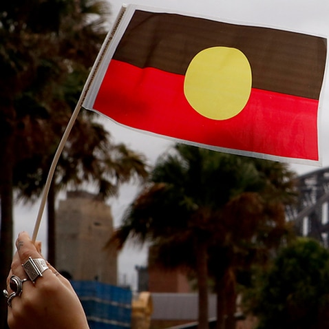 A woman holds an Australian Aboriginal Flag during a demonstration in Sydney, Saturday, June 2, 2018. The demonstrators are calling for the Australian Aboriginal Flag to be flown atop Sydney Harbour Bridge. (AAP Image/Daniel Munoz) NO ARCHIVING