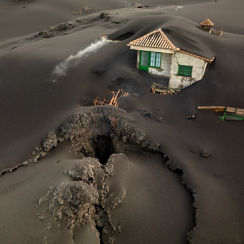A fissure is seen next to a house covered with ash on the Canary island of La Palma, Spain