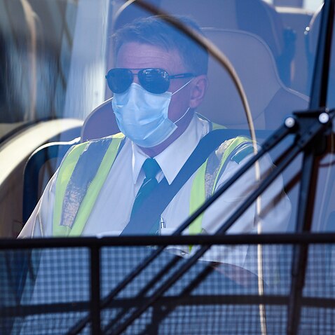 A charter bus driving wearing a mask is seen waiting to take Australian residents returning from India to begin their 14-day imposed quarantine, after arriving at Sydney International Airport in Sydney, Friday, May 8, 2020. (AAP Image/Bianca De Marchi) NO