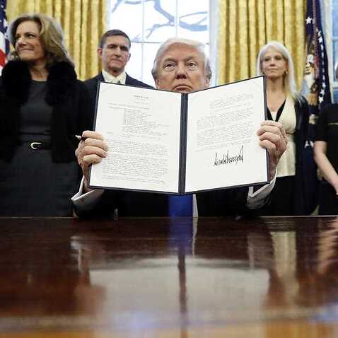 FILE - In this Saturday, Jan. 28, 2017 file photo, President Donald Trump holds up a signed Presidential Memorandum in the Oval Office in Washington. 