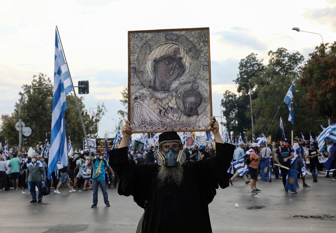 An Orthodox monk wearing a mask raises an icon during clashes with police at the northern Greek city of Thessaloniki.