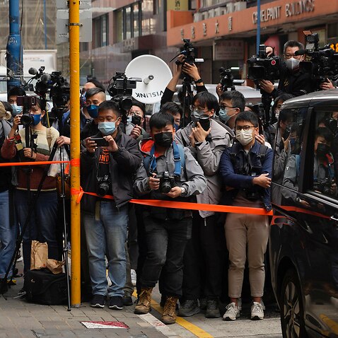 Journalists wait outside the building of the Stand News office