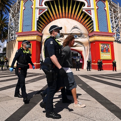 Victorian Police officers detain a person outside of Luna Park in Melbourne.