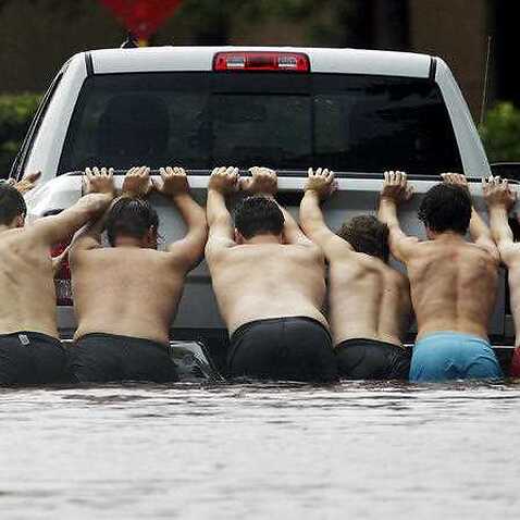 People push a stalled pickup to through a flooded street in Houston, after Tropical Storm Harvey dumped heavy rains Sunday, Aug. 27, 2017. 