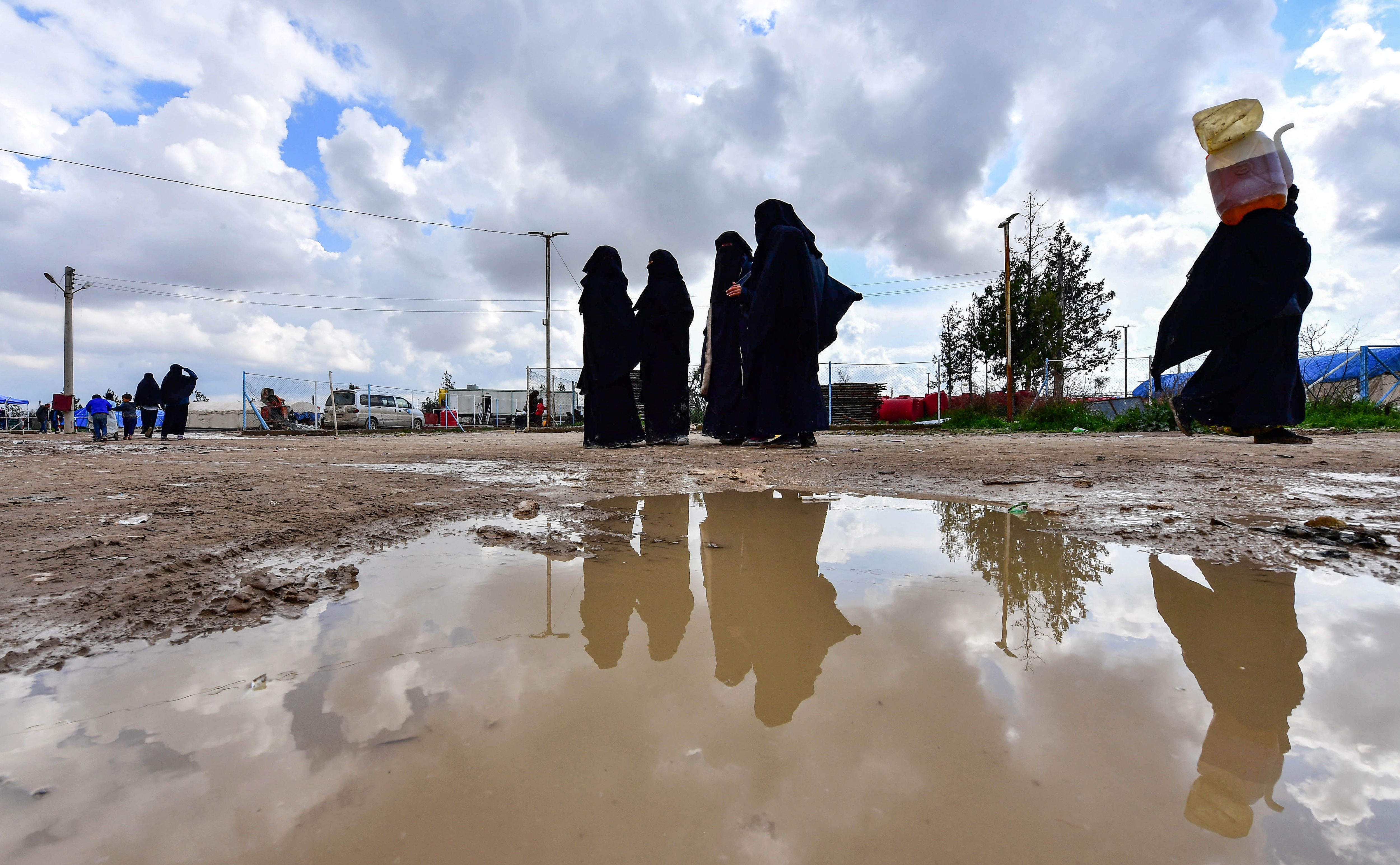 Women living inside Al-Hawl camp which houses relatives of Islamic State group members, walk inside the site in al-Hasakeh governorate in northeastern Syria.