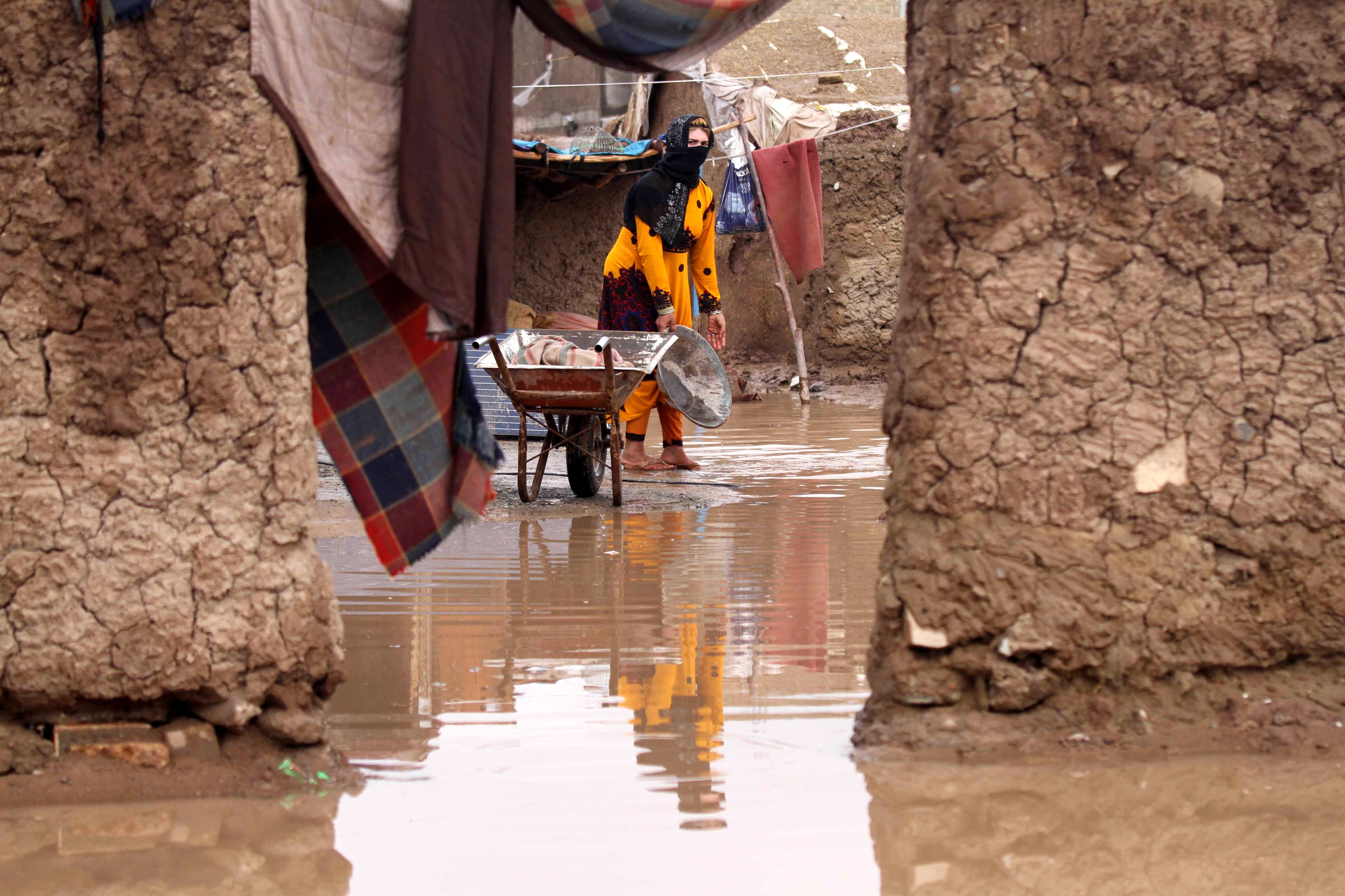 Afghan woman throws flood water out of her home in Herat, Afghanistan.
