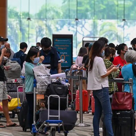 Passengers queue to check-in for their flights prior to departure